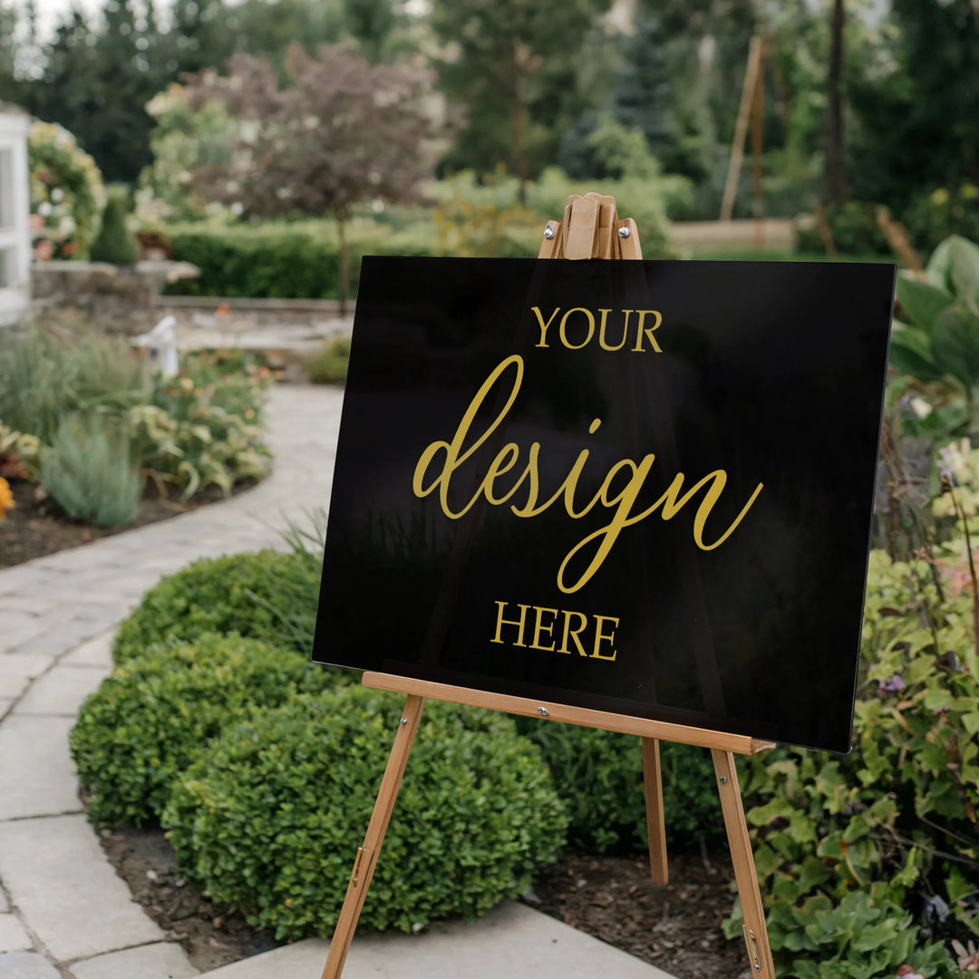 Customizable black acrylic sign with gold text on wooden easel in garden setting