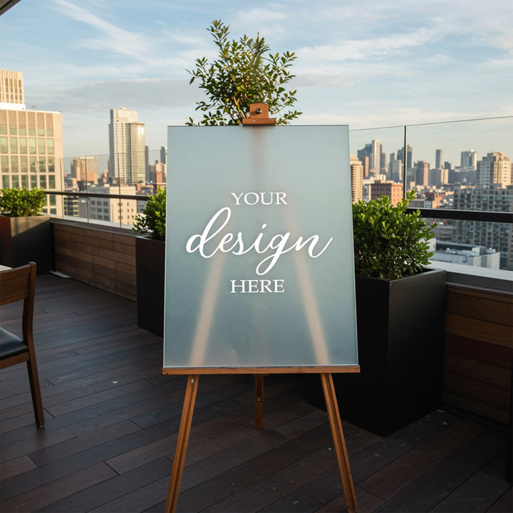 Frosted acrylic sign on wooden easel with your design here text on rooftop patio with city skyline