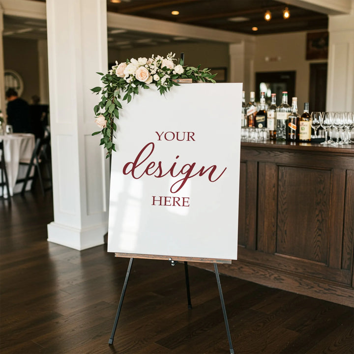 Blank wedding welcome sign with floral decoration on easel beside bar in event venue