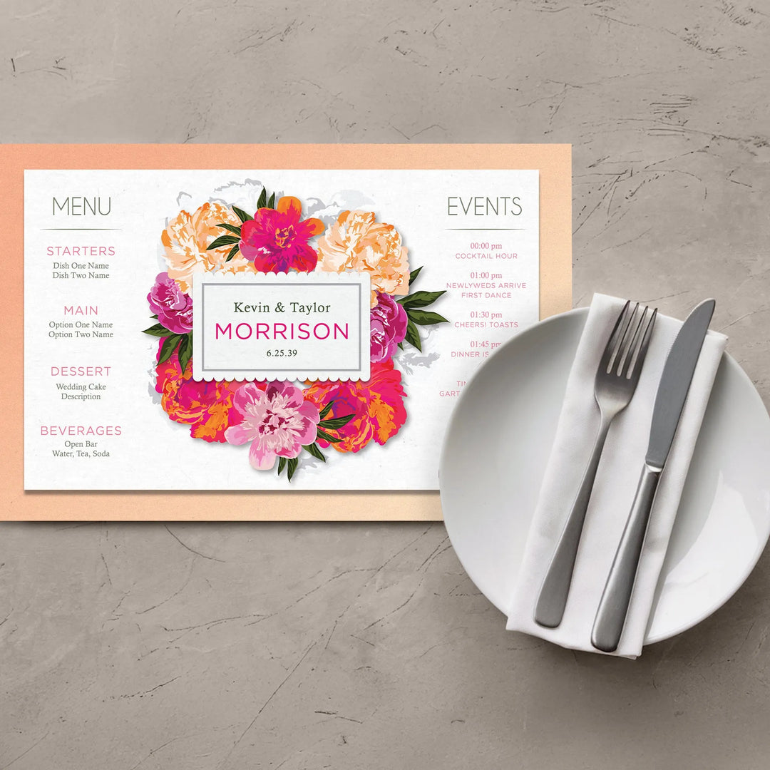 Vibrant pink and orange floral placemat with wedding menu and event details beside a white plate