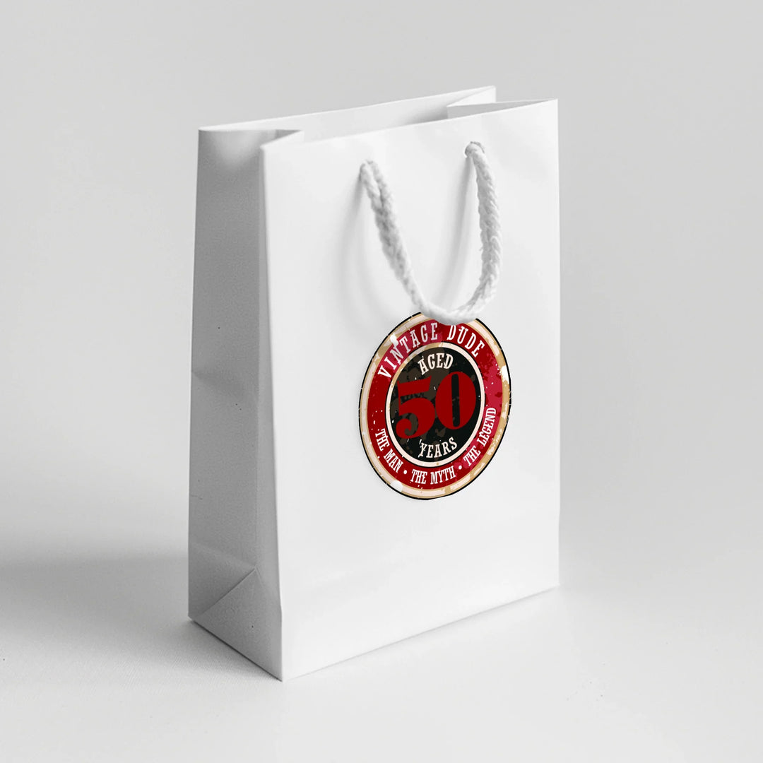 White gift bag with vintage dude 50th birthday favor label on front