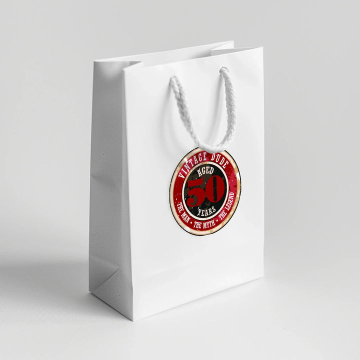 White gift bag with vintage dude 50th birthday favor label on front