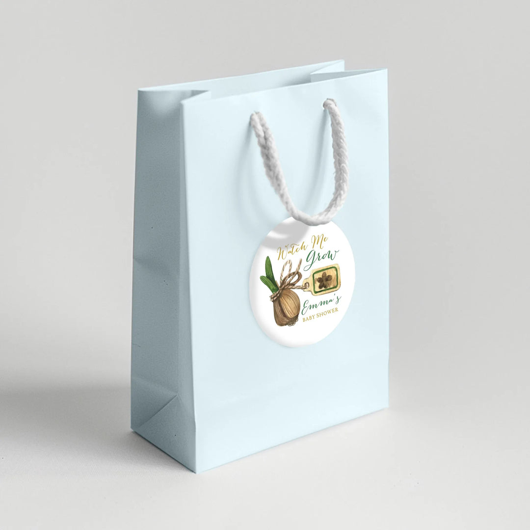 Light blue gift bag with 'Watch Me Grow' baby shower favor label and rope handle
