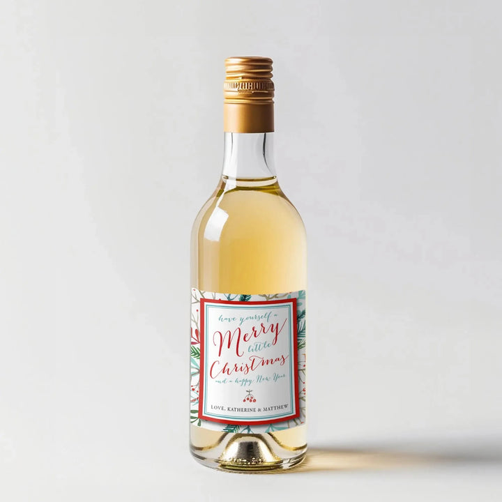 Mini wine bottle with watercolor Christmas label and gold cap on white background