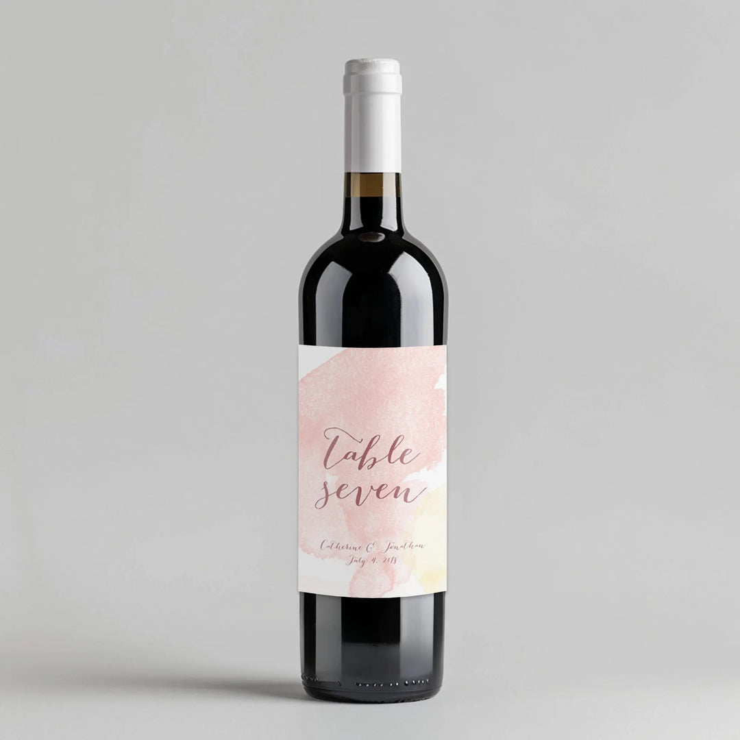Wine bottle with watercolor script table number label on a light gray background