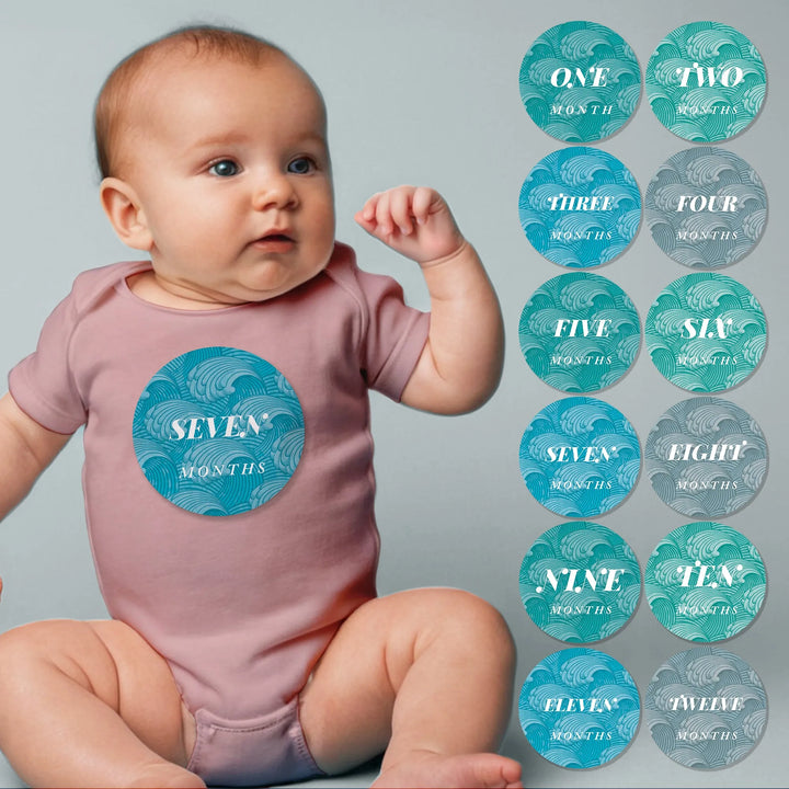 Baby wearing pink onesie with "seven months" ocean wave milestone sticker, monthly wave stickers set.
