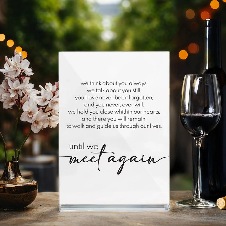 Memorial wedding sign with heartfelt text, flowers in vase, wine bottle, and glass on table