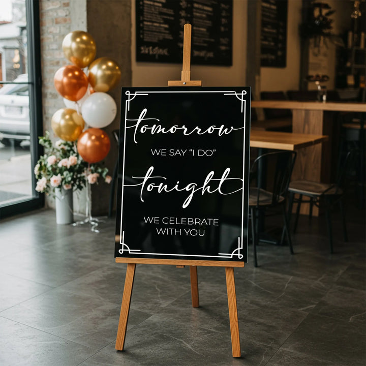 Wedding rehearsal welcome sign on wooden easel in modern venue with gold, bronze, and white balloons