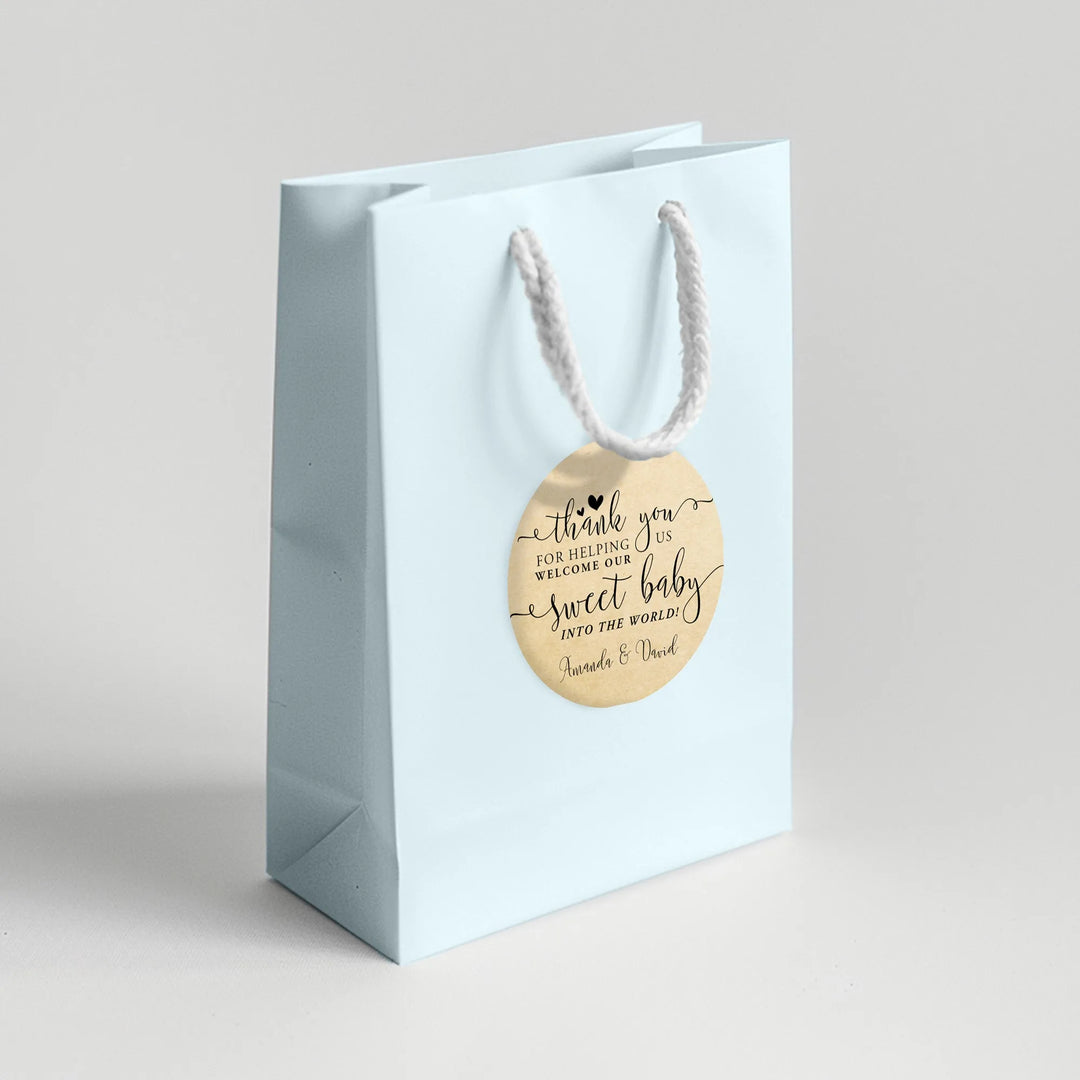 Light blue baby shower favor bag with round thank you label and white rope handle