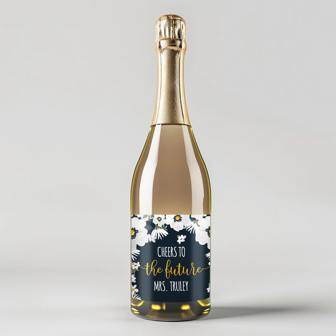 Champagne bottle with gold foil and white floral label reading 'Cheers to the Future Mrs. Truly'.