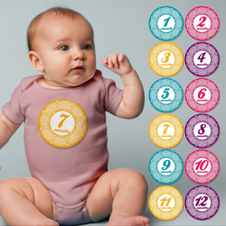 Baby in pink onesie wearing a yellow lace baby month sticker with monthly milestone stickers set.
