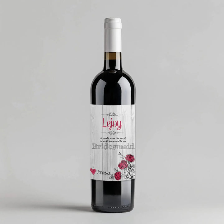 Wine bottle with white wood bridesmaid label, red floral accents, and personalized name.
