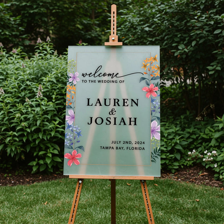 Wedding welcome sign for Lauren and Josiah on easel with floral design in garden setting