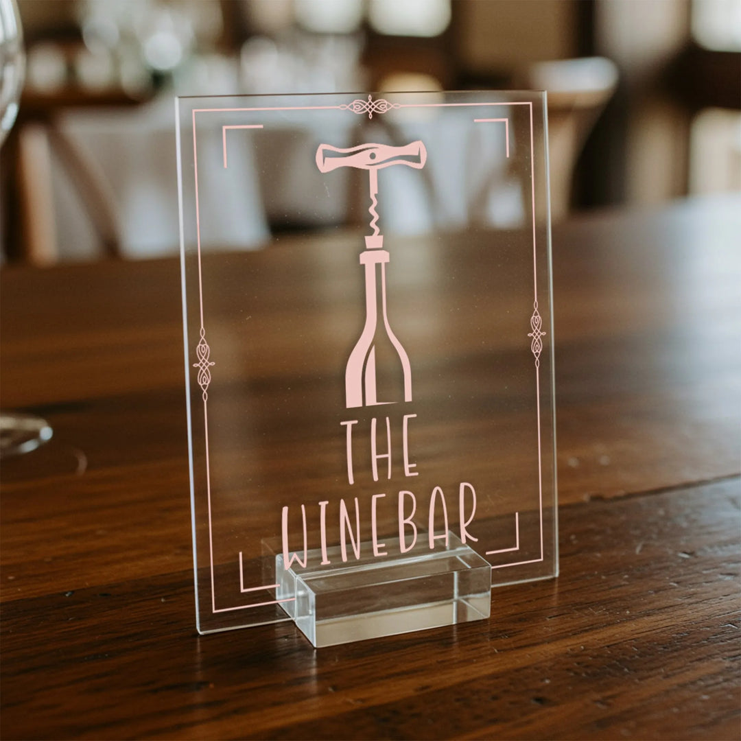 Clear acrylic wedding table sign with pink wine bottle and corkscrew design, labeled The Winebar