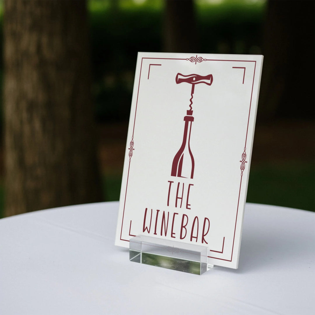 Wedding table sign reading The Wine Bar with wine bottle and corkscrew graphic on white stand