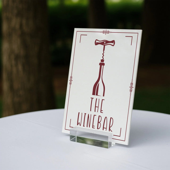 Wedding table sign reading The Wine Bar with wine bottle and corkscrew graphic on white stand
