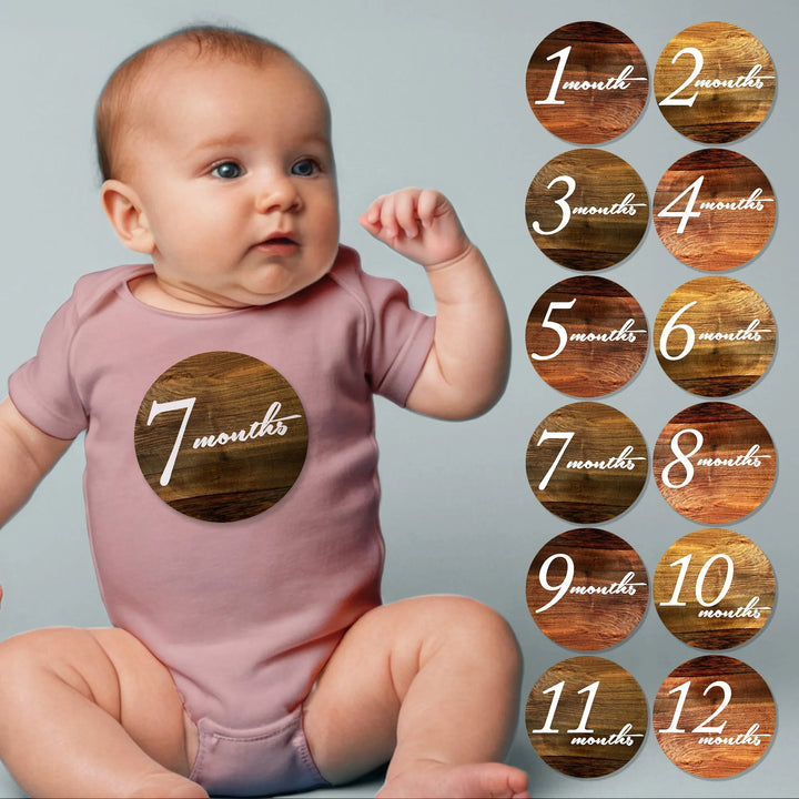 Baby wearing pink onesie with wood script baby month sticker, wood grain milestone stickers set