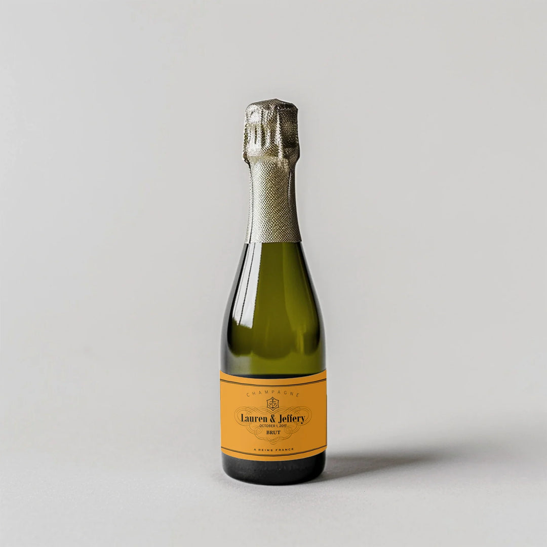 Mini champagne bottle with custom yellow label on light background