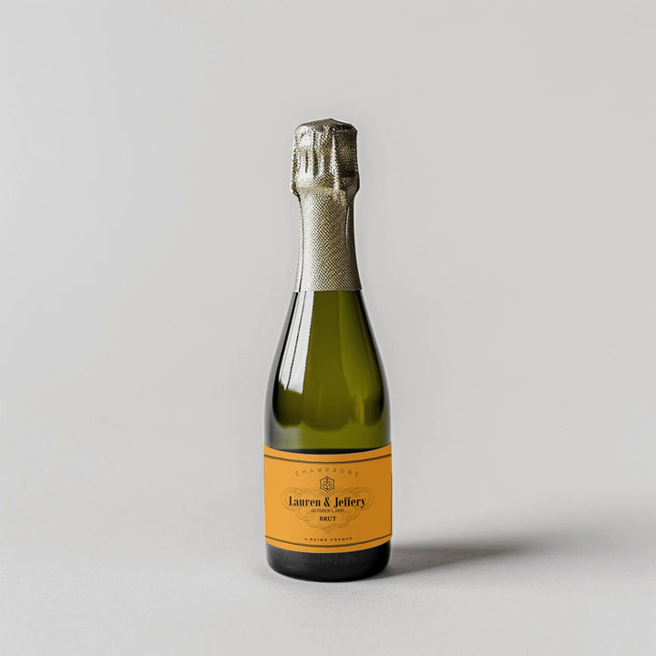 Mini champagne bottle with custom yellow label on light background