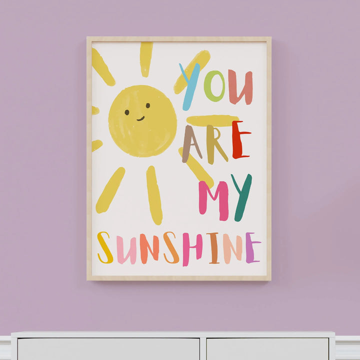 Colorful nursery wall art with a smiling sun and text You Are My Sunshine in playful fonts